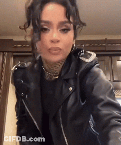 A Woman In A Black Leather Jacket Is Standing In A Kitchen . GIF