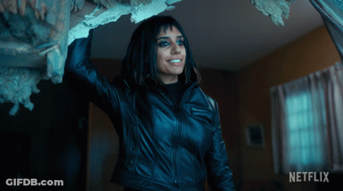 A Woman In A Black Leather Jacket Is Standing In A Room With A Netflix Logo On The Bottom GIF