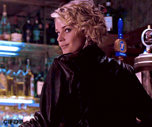 A Woman In A Black Leather Jacket Stands In Front Of A Beer Tap That Says Budweiser GIF