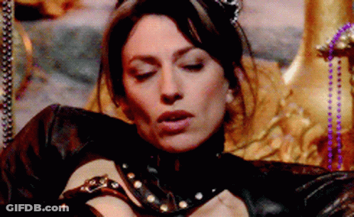 A Woman In A Black Leather Outfit Is Laying On A Throne With Her Eyes Closed GIF