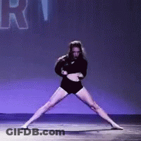 A Woman In A Black Outfit Is Dancing On A Stage With The Word Rhythm In The Background . GIF
