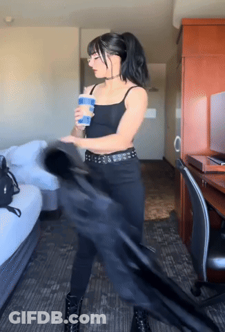 A Woman In A Black Outfit Is Holding A Blue Cup GIF