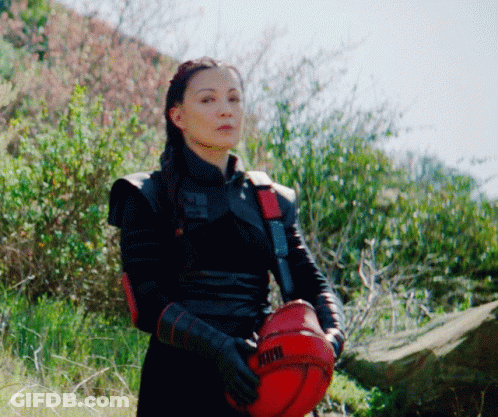 A Woman In A Black Outfit Is Holding A Red Helmet That Says Kthx GIF
