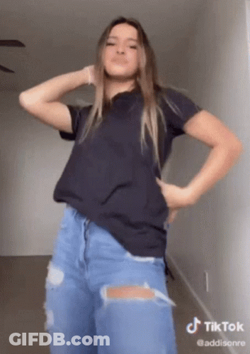A Woman In A Black Shirt And Ripped Jeans Is Dancing On A Tiktok GIF