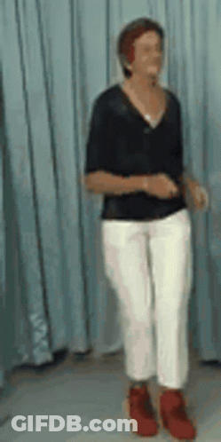 A Woman In A Black Shirt And White Pants Is Dancing GIF