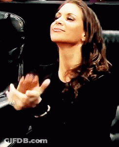 A Woman In A Black Shirt Is Clapping Her Hands In The Air GIF