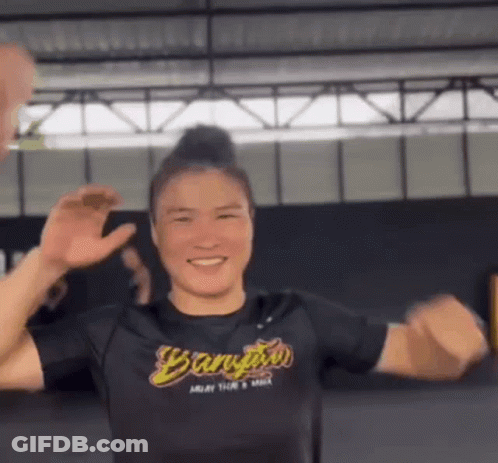 A Woman In A Black Shirt Is Dancing In A Gym . GIF