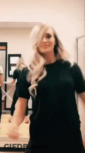A Woman In A Black Shirt Is Dancing In A Room . GIF