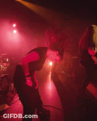 A Woman In A Black Shirt Is Dancing On Stage GIF