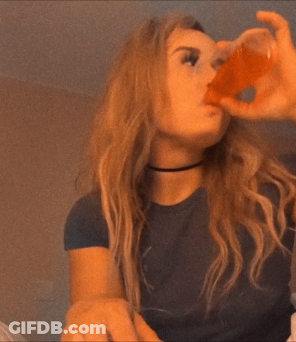 A Woman In A Black Shirt Is Drinking From A Small Cup GIF