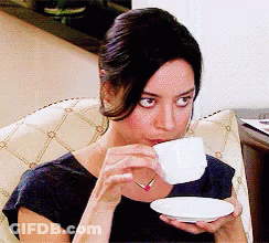 A Woman In A Black Shirt Is Drinking From A White Cup GIF