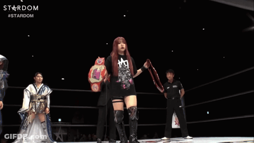 A Woman In A Black Shirt Is Holding A Wrestling Belt With The Word Stardom On It GIF