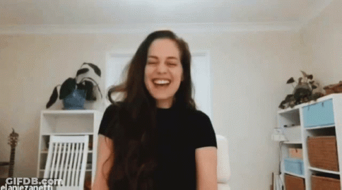 A Woman In A Black Shirt Is Laughing In A Room With The Name Elaniezanetti On The Bottom GIF