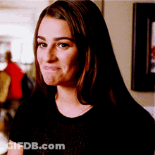 A Woman In A Black Shirt Is Making A Funny Face And Looking At The Camera . GIF