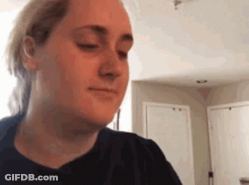 A Woman In A Black Shirt Is Making A Funny Face In A Kitchen . GIF