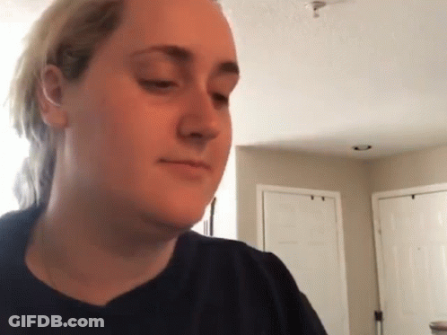 A Woman In A Black Shirt Is Making A Funny Face In A Living Room . GIF
