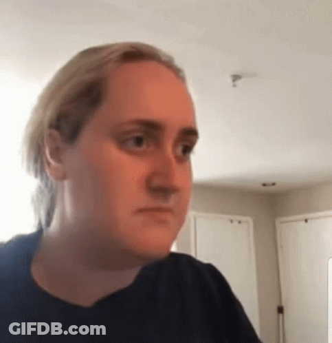 A Woman In A Black Shirt Is Making A Funny Face In A Room . GIF