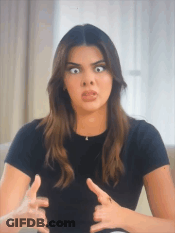 A Woman In A Black Shirt Is Making A Funny Face With Her Hands GIF