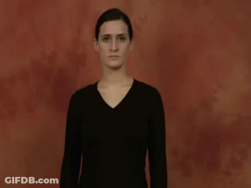 A Woman In A Black Shirt Is Making A Hand Gesture With Her Hands . GIF