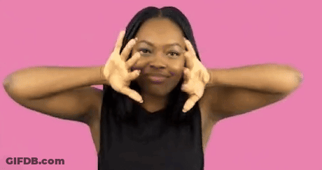 A Woman In A Black Shirt Is Making A Peace Sign With Her Hands . GIF
