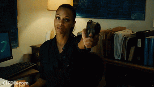 A Woman In A Black Shirt Is Pointing A Gun At Someone GIF