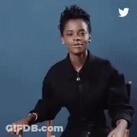 A Woman In A Black Shirt Is Sitting In A Chair With A Twitter Bird Flying In The Background . GIF