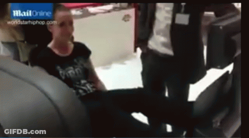 A Woman In A Black Shirt Is Sitting In The Back Seat Of A Car In Front Of A Blue Sign That Says Mail Online GIF