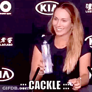 A Woman In A Black Shirt Is Smiling And Holding A Bottle With The Word Cackle Written On The Bottom GIF