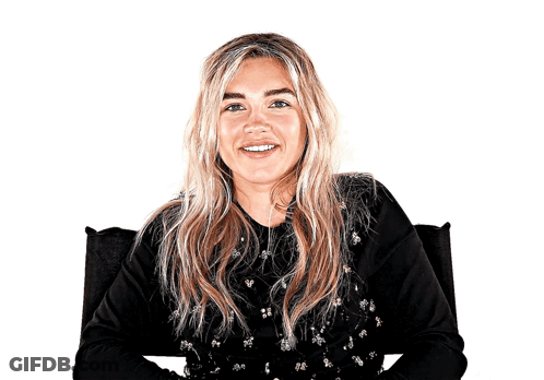 A Woman In A Black Shirt Is Smiling And Sitting In A Chair GIF