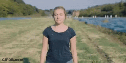 A Woman In A Black Shirt Is Standing In A Field . GIF