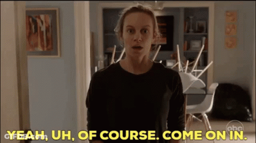 A Woman In A Black Shirt Is Standing In A Living Room And Says Yeah Uh Of Course Come On In GIF