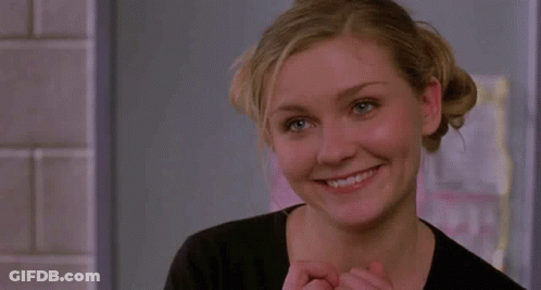 A Woman In A Black Shirt Looks At The Camera And Smiles GIF