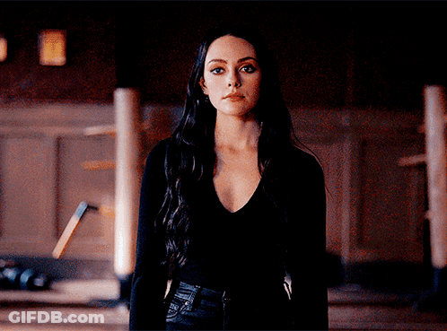 A Woman In A Black Shirt Stands In A Dark Room GIF