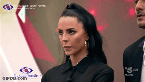 A Woman In A Black Shirt Stands In Front Of A Sign That Says 5 Hd GIF
