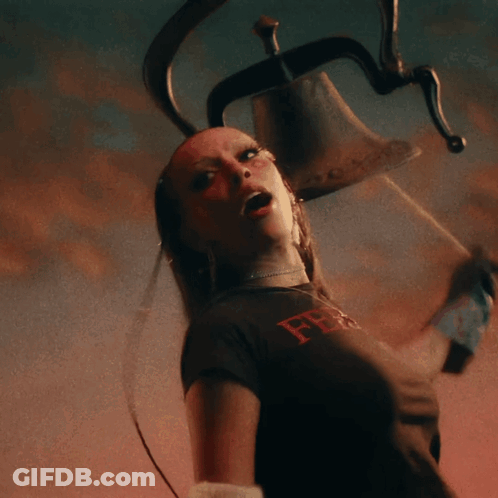 A Woman In A Black Shirt With The Letter F On It Holds A Bell GIF