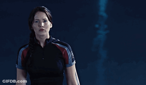 A Woman In A Black Shirt With The Word Hunger Games On Her Sleeve GIF