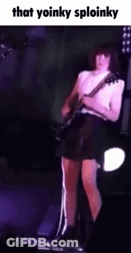A Woman In A Black Skirt Is Playing A Guitar On Stage . GIF