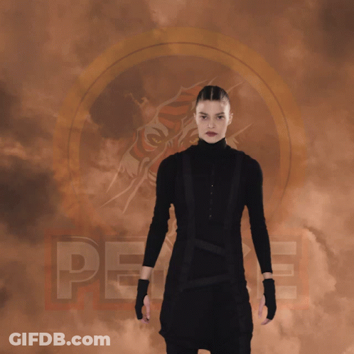 A Woman In A Black Suit Is Doing A Split With The Word Peace Behind Her GIF