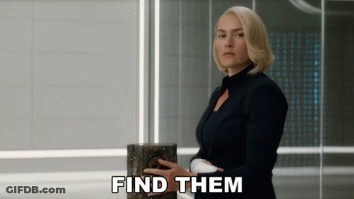 A Woman In A Black Suit Is Holding A Box With The Words Find Them Below Her GIF