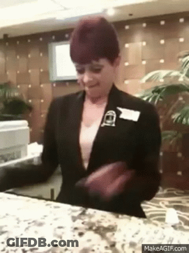 A Woman In A Black Suit Is Standing At A Counter In A Hotel Lobby . GIF