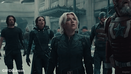 Woman In Black Suit With X On Chest In Front Of Soldiers GIF