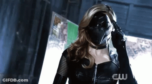 A Woman In A Black Superhero Costume Is Wearing A Mask And Gloves . GIF