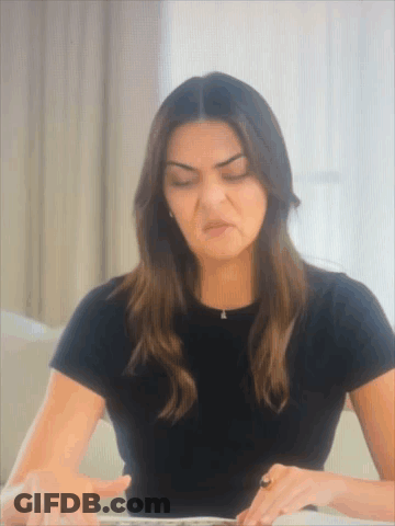 A Woman In A Black T-Shirt Is Making A Funny Face GIF