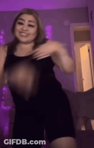 A Woman In A Black Tank Top Is Dancing In A Room With Purple Lights GIF