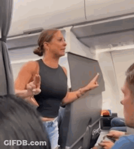 A Woman In A Black Tank Top Is Giving The Middle Finger On An Airplane GIF