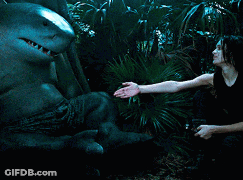 A Woman In A Black Tank Top Is Holding A Shark GIF