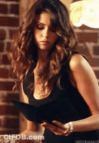 A Woman In A Black Tank Top Is Holding A Wallet And A Book . GIF