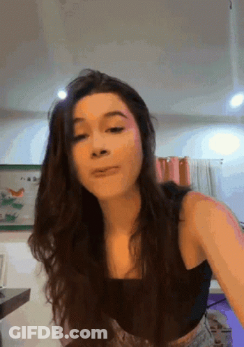 A Woman In A Black Tank Top Is Making A Face GIF