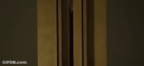 A Woman In A Black Tank Top Is Standing In Front Of A Window . GIF
