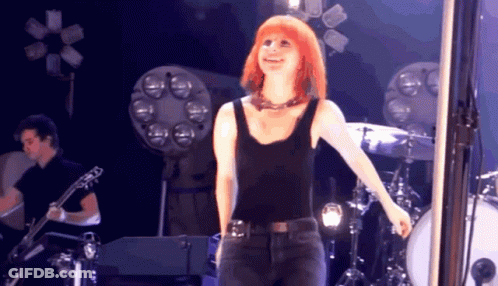 A Woman In A Black Tank Top Is Standing On Stage GIF